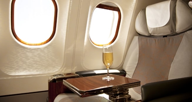 Luxus in der Business Class – Bequemer Sitz mit viel Platz und einem Glas Champagner für ein exklusives Reiseerlebnis.