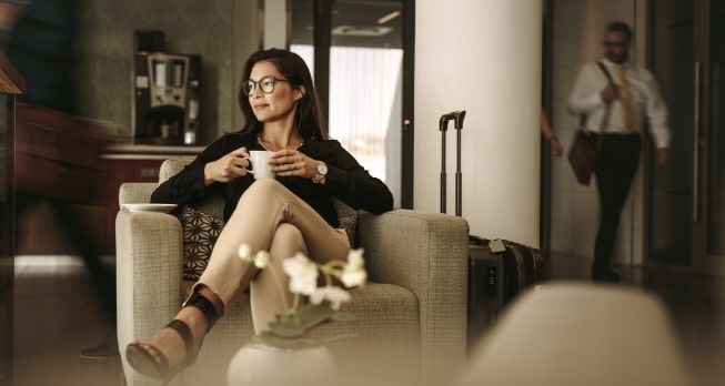 Luxus in der Business Class Lounge - Eine Frau trinkt ein Heißgetränk in deinem bequemen Sessel