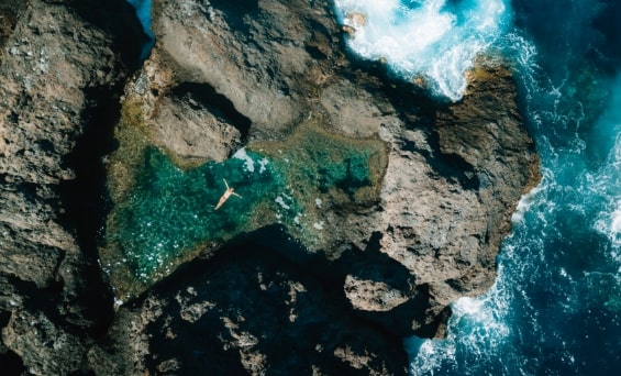 Entspannung pur: Eine Frau schwimmt im türkisblauen Meer, umgeben von beeindruckenden Felsen